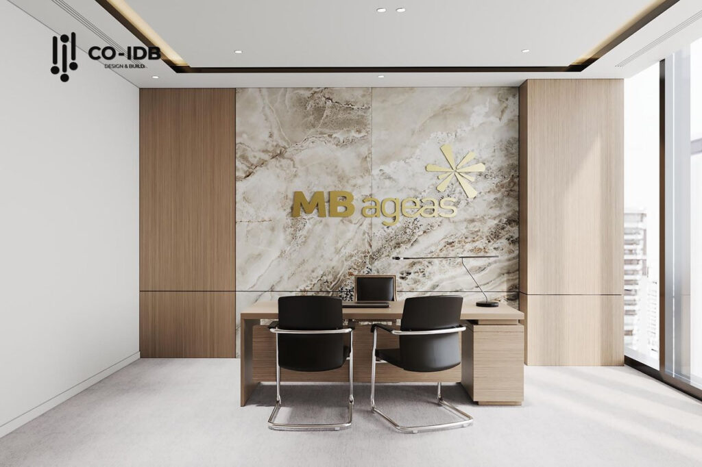 Bàn làm việc giám đốc MB Ageas Life đặt giữa vách đá marble logo vàng nổi bật, mang phong cách tối giản hiện đại.