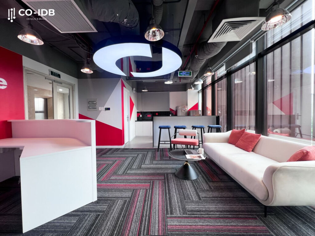 Sàn được trải thảm họa tiết sọc chéo màu xám và đỏ. Bức tường phía sau được trang trí bằng các hình khối tam giác màu trắng và đỏ.