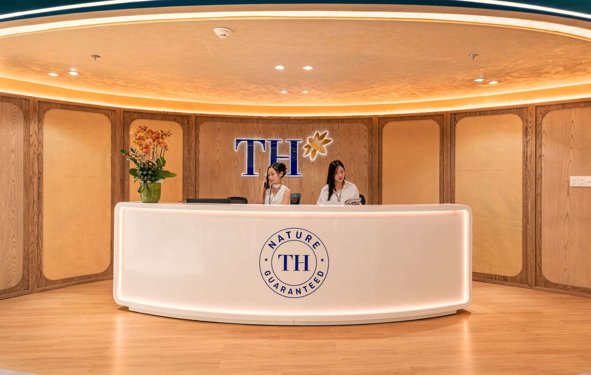 Thiết kế sảnh lễ tân văn phòng tập đoàn TH sang trọng với logo nổi bật và quầy kính cao cấp.
